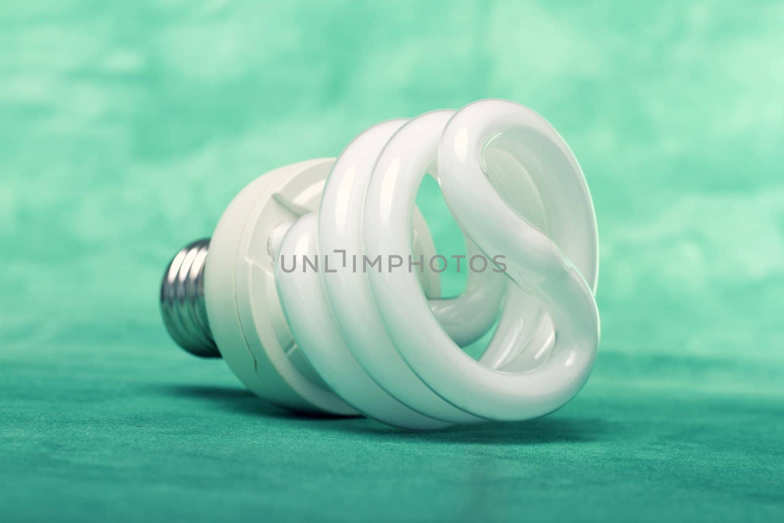 Close view of a curly light bulb on a green background.