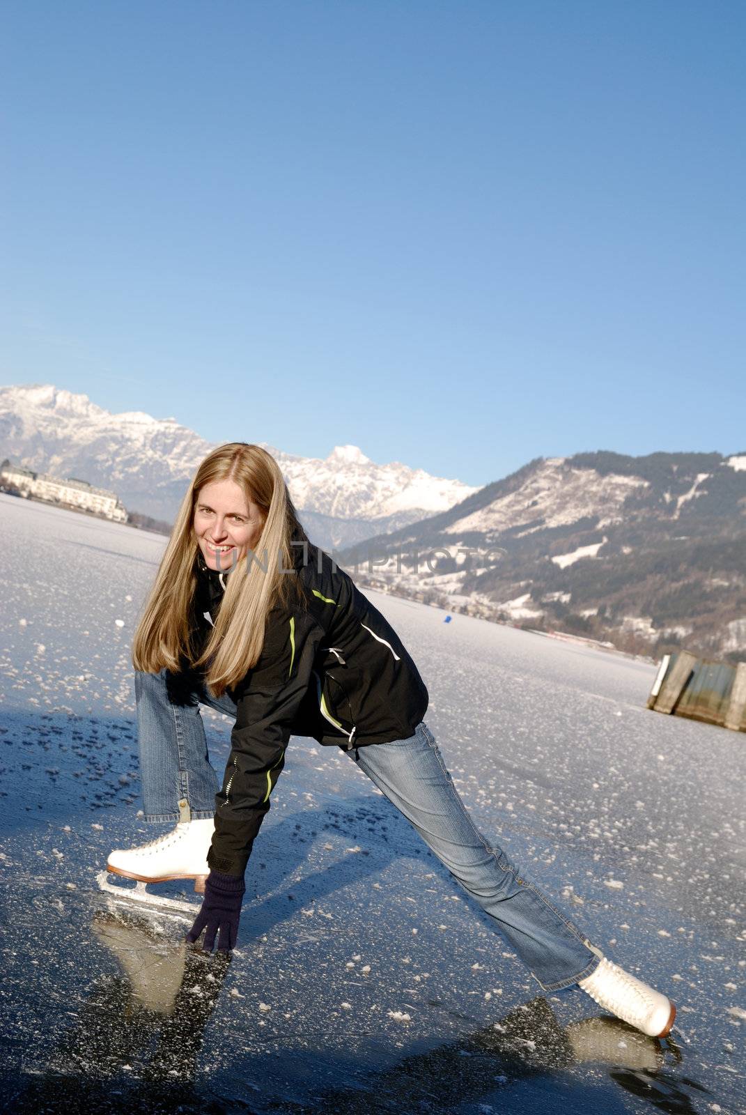 Young woman figure skating at frozen lake of zell am see in austria