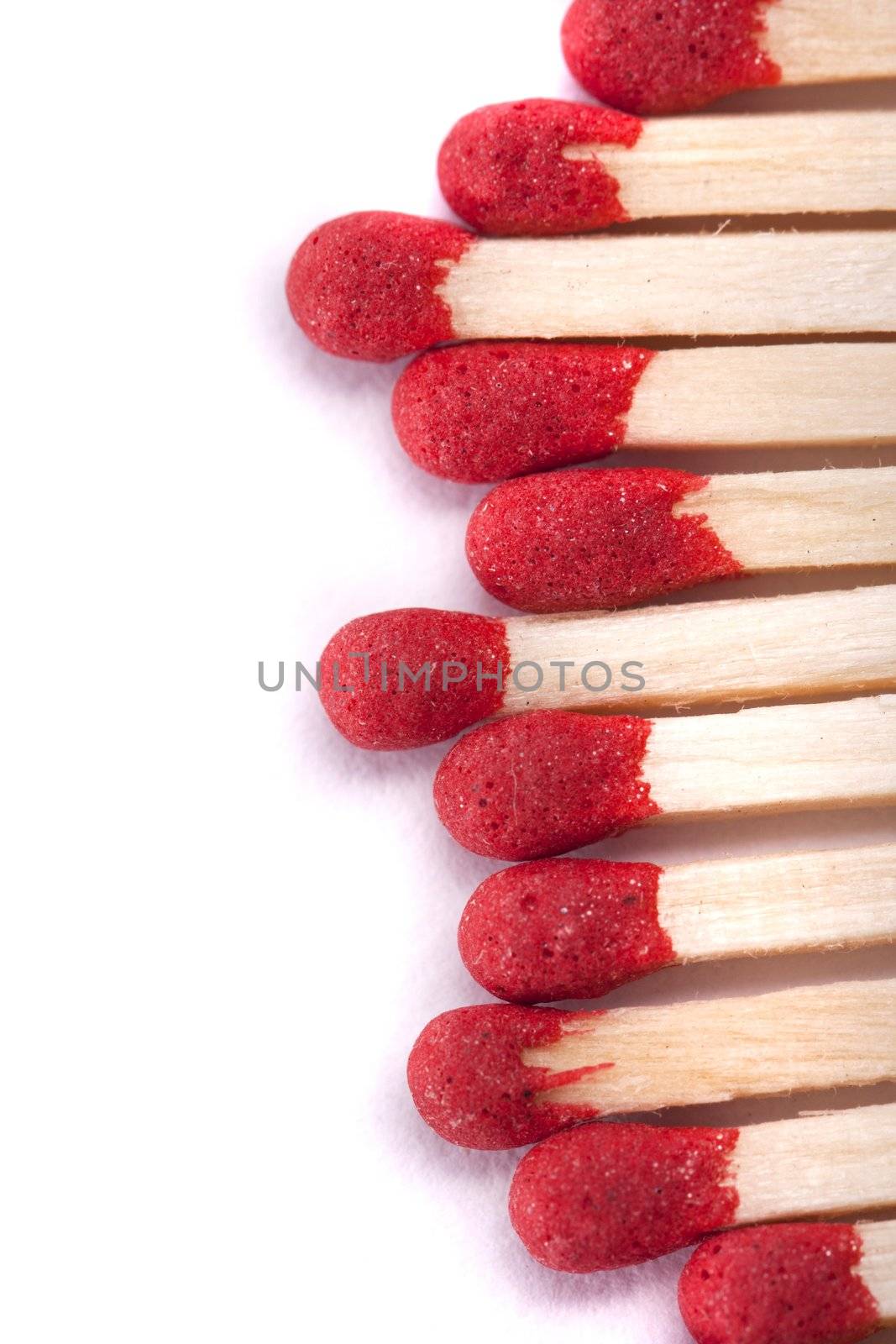 Close up view of a bunch of matches with red heads on a white background.