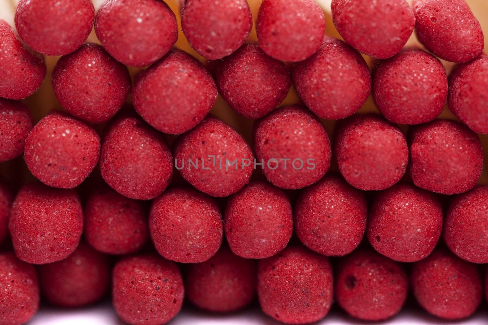 Close up view of a bunch of matches with red heads on a white background.