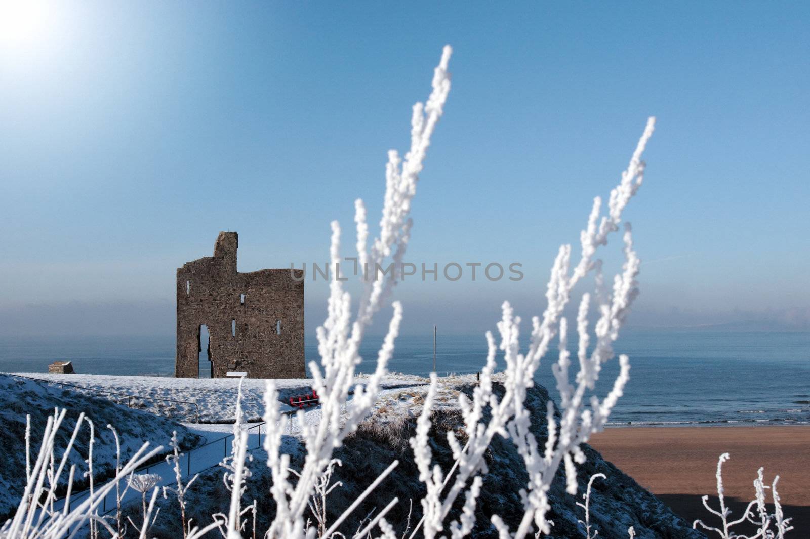 a seasonal snow covered view of atlantic ocean and ballybunion castle beach and cliffs on a frosty snow covered winters day
