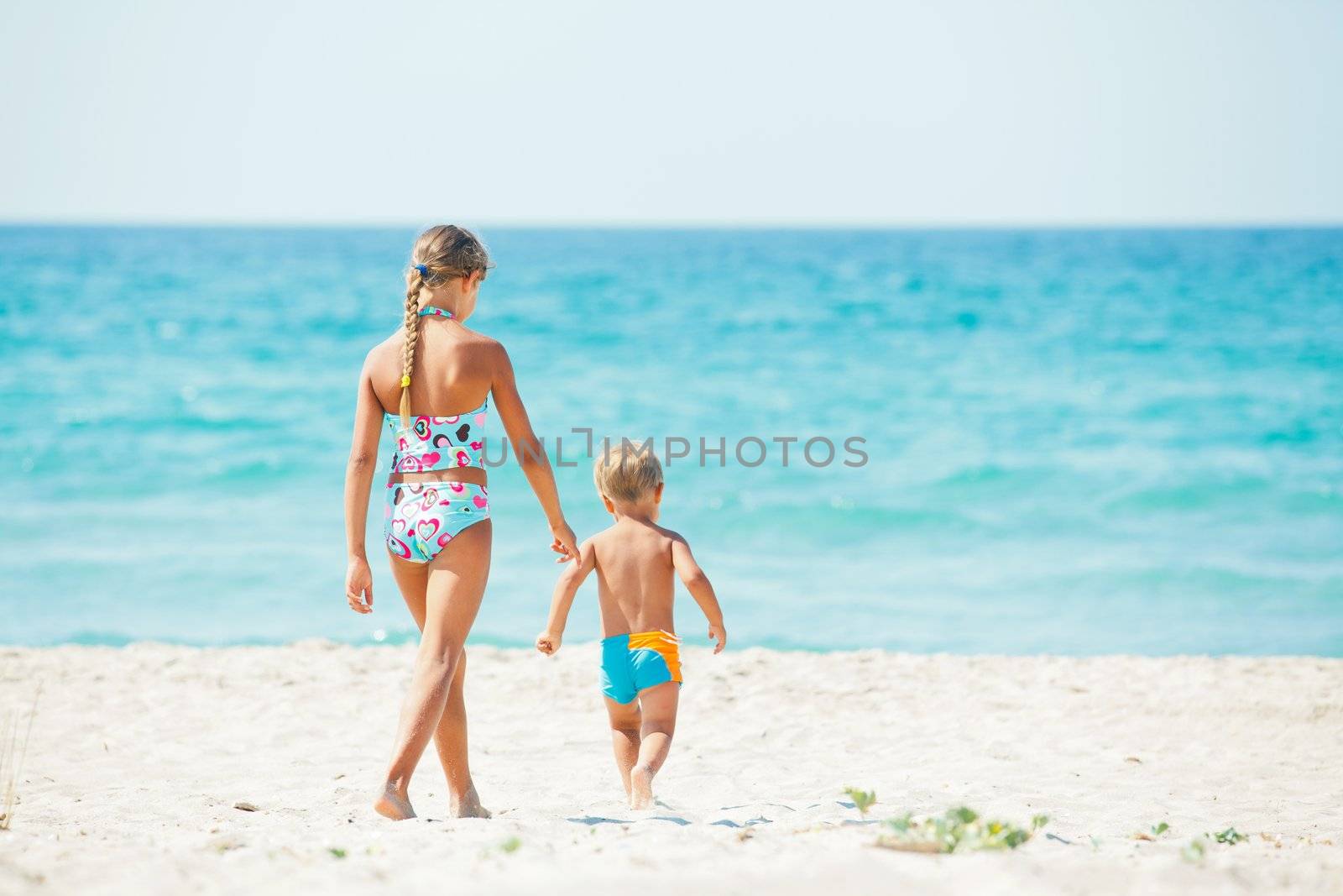 Young beautiful girl and boy playing happily at pretty beach