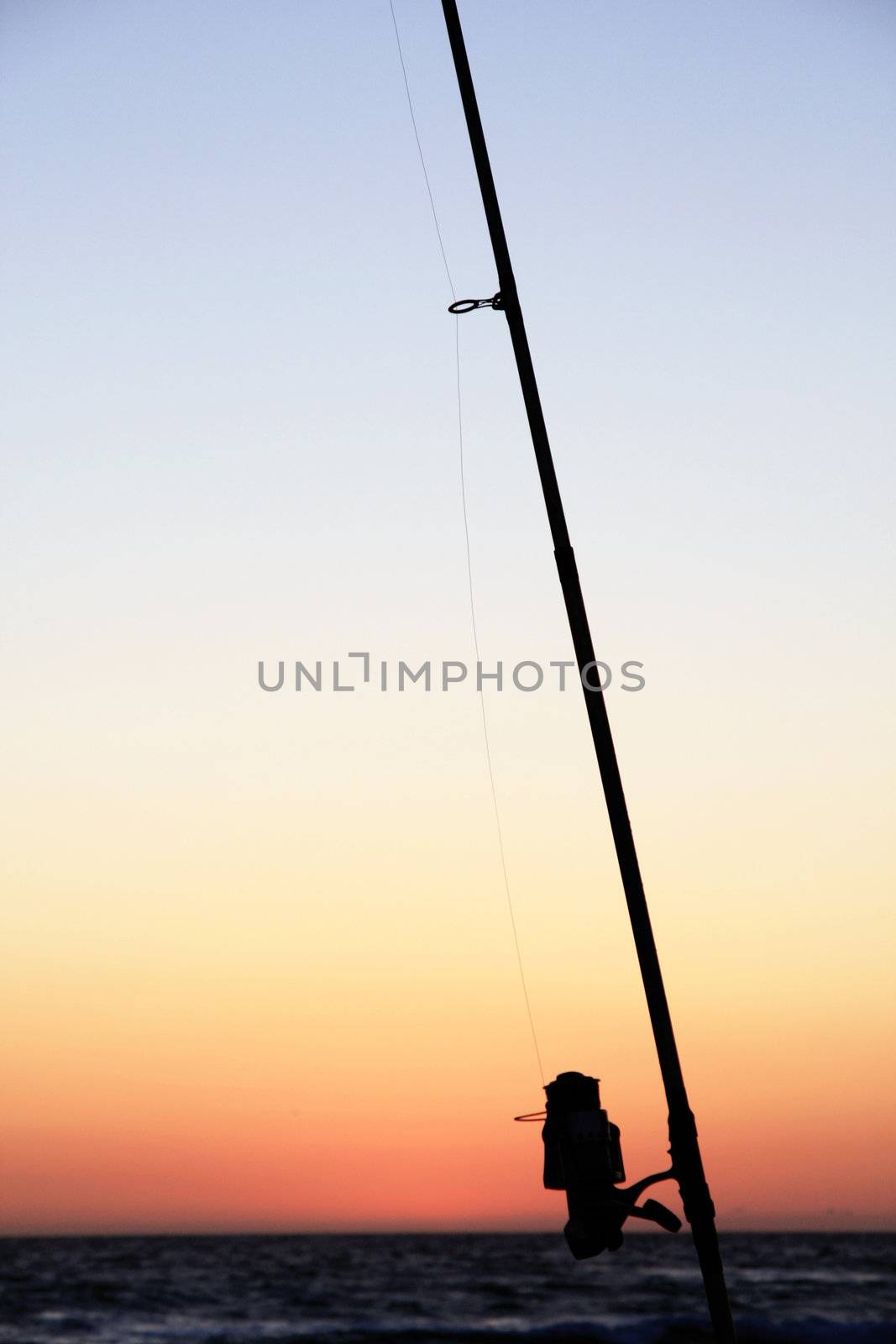 View of a fishing pole silhouette near the shoreline.