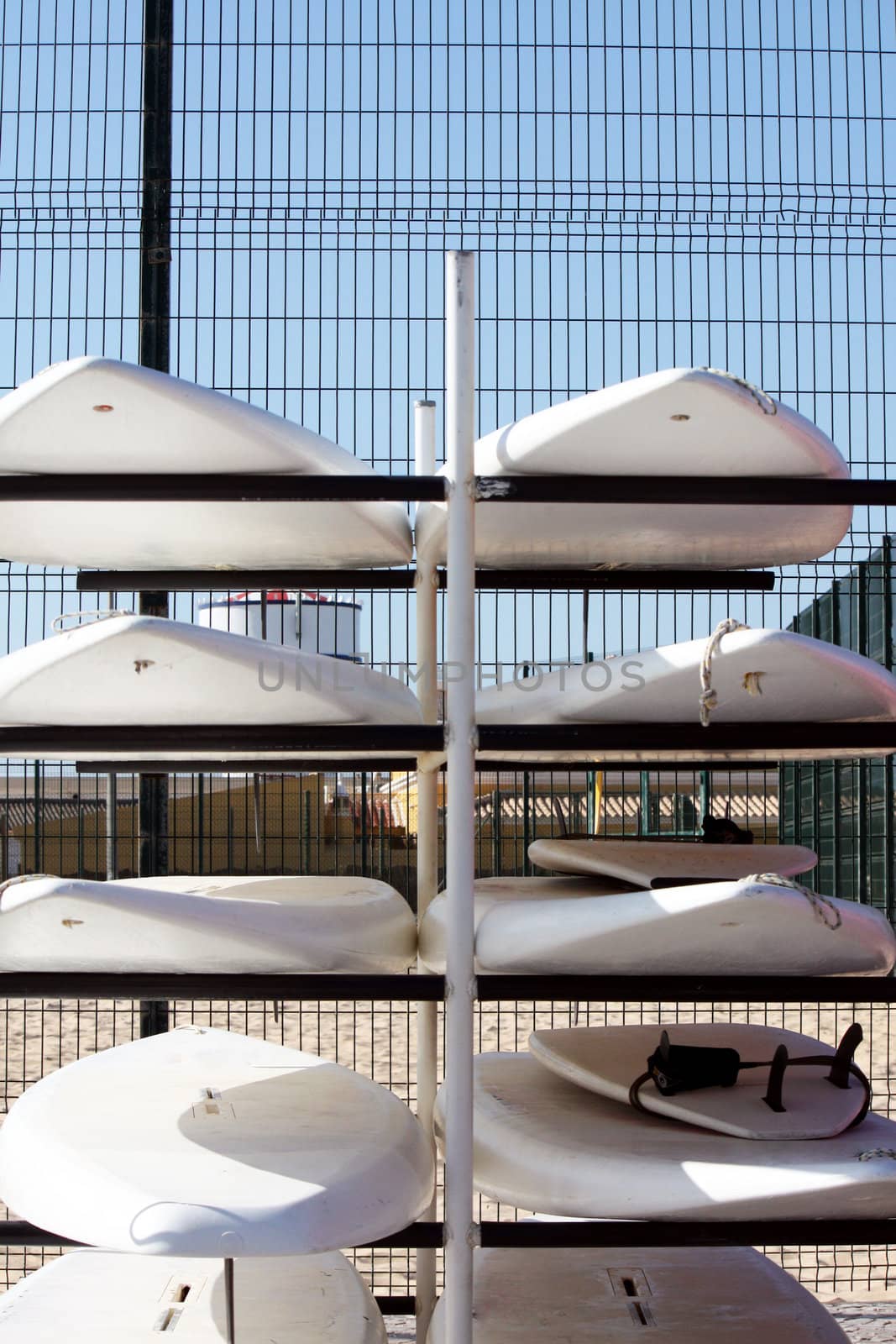 View of a bunch of aligned surfer boards piled on top of each other.