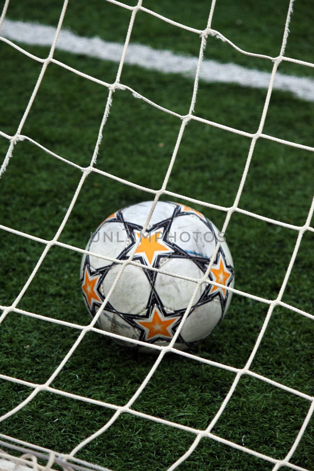 View of a soccer ball inside the goalpost on the grass.