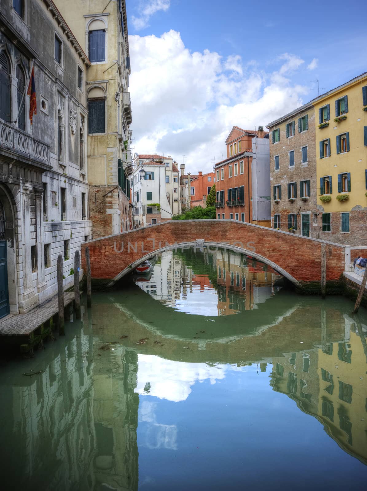 Reflections in still canal of bridge and old buildings in Venice Italy