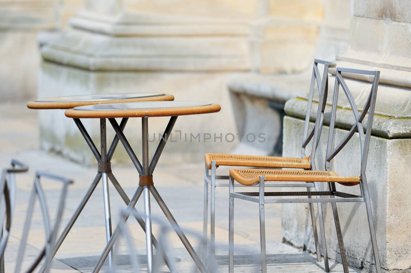 Round tables and wicker chairs in cafe in Paris. Photo with tilt-shift effect