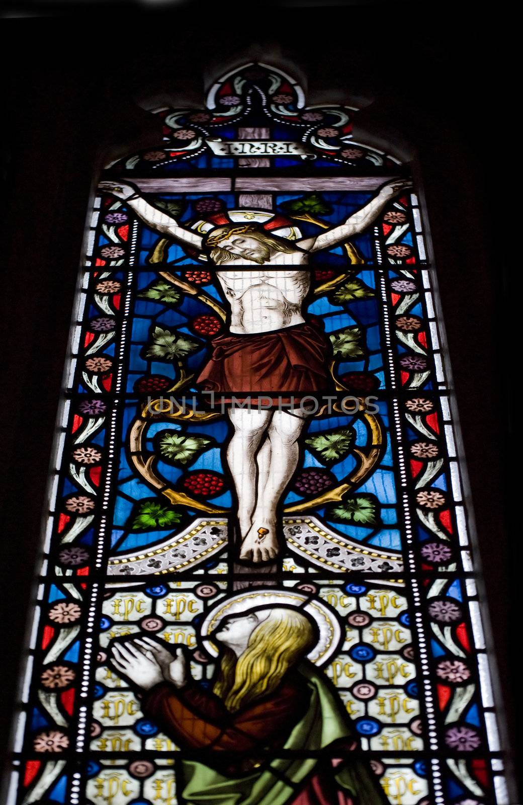 Beautiful stained glass window depicting Jesus on the cross with by Veneratio