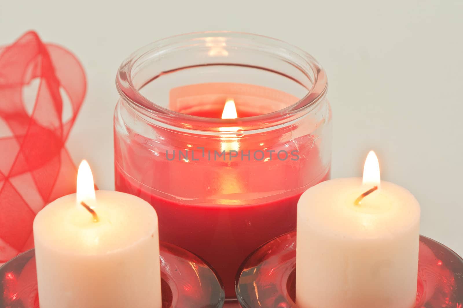 Set of three candles with flame and red ribbon
