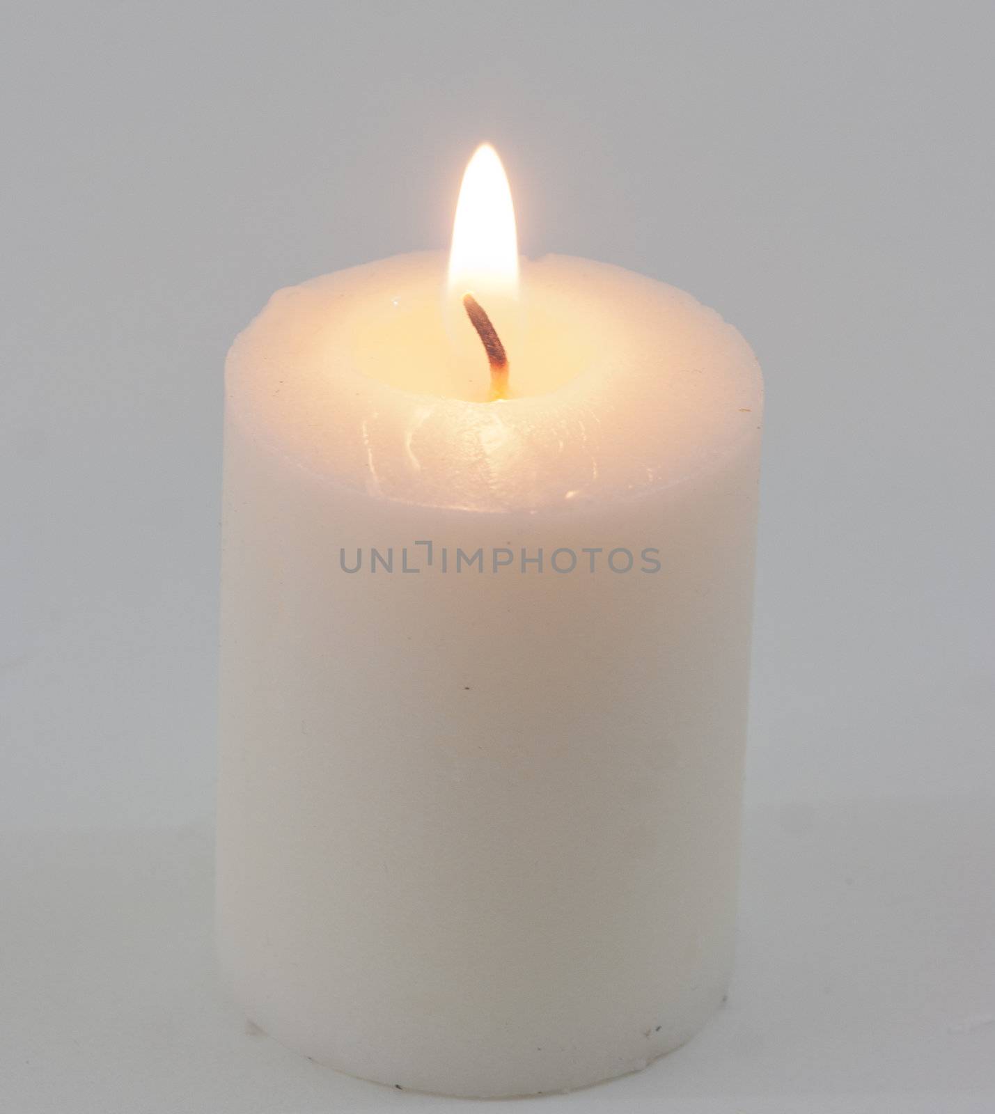 White candle with flame on white background