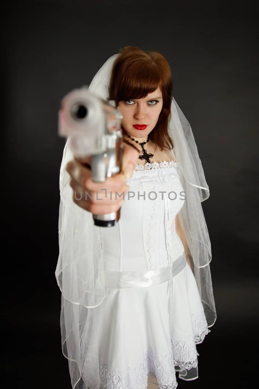 Young bride threatens us with a gun on black background