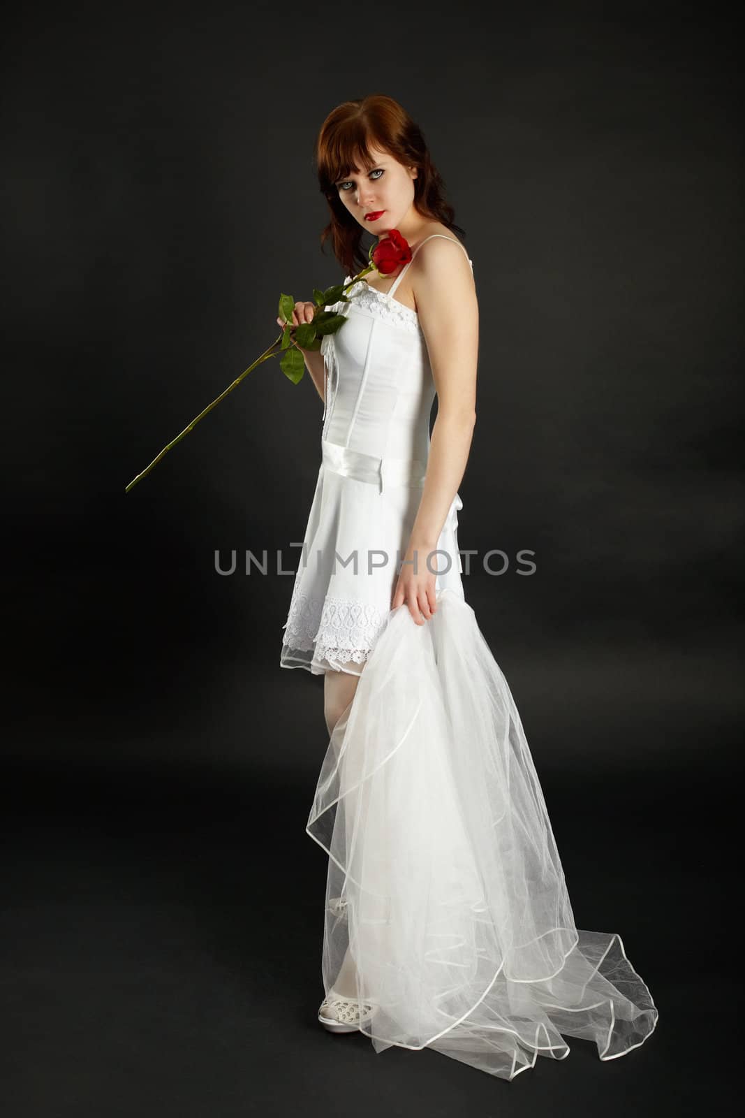 Young bride with a rose and a veil on a black background