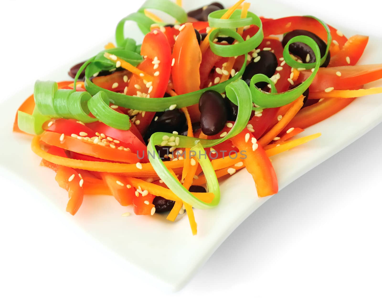 A salad of tomatoes, sweet peppers, red beans, carrots with sesame