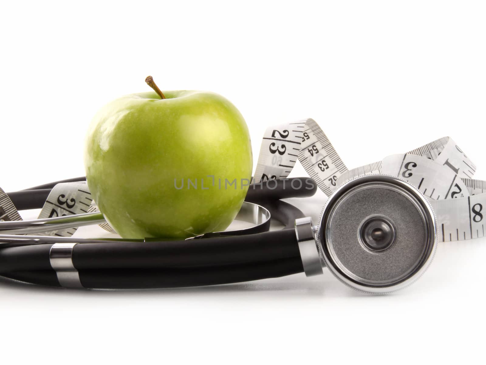 Green apple and measuring tape with stethoscope on white by Sandralise