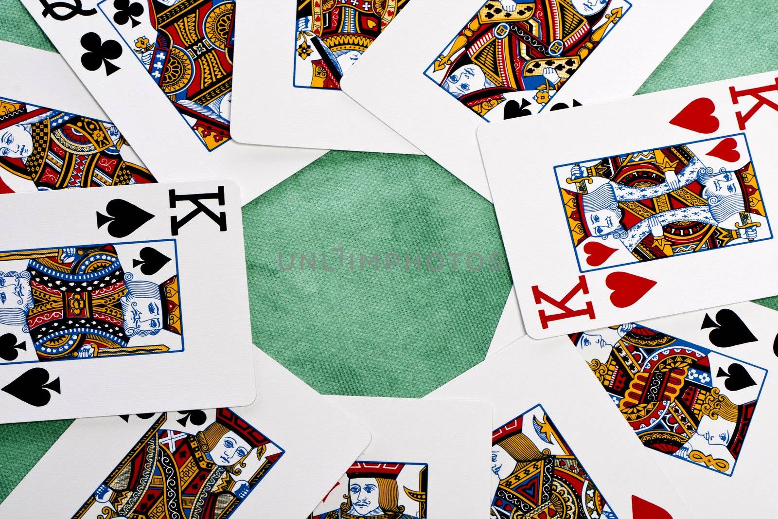 Close up view of a bunch face cards spread on a green cloth table.