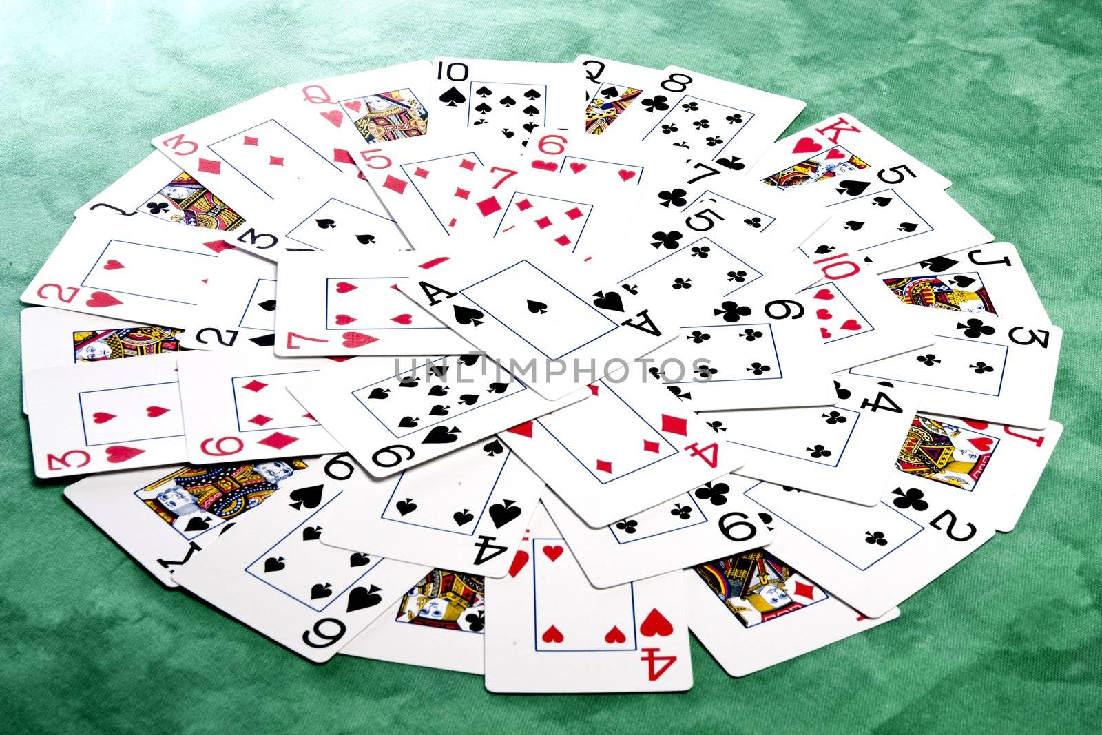 Close up view of a bunch cards spread on a green cloth table forming a circle.