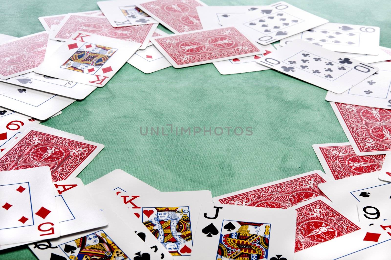 Close up view of a bunch cards spread on a green cloth table.