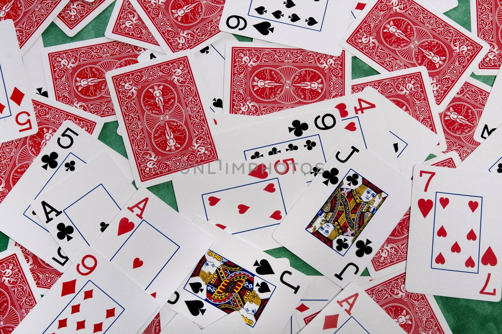 Close up view of a bunch of playing cards spread on a green cloth table.