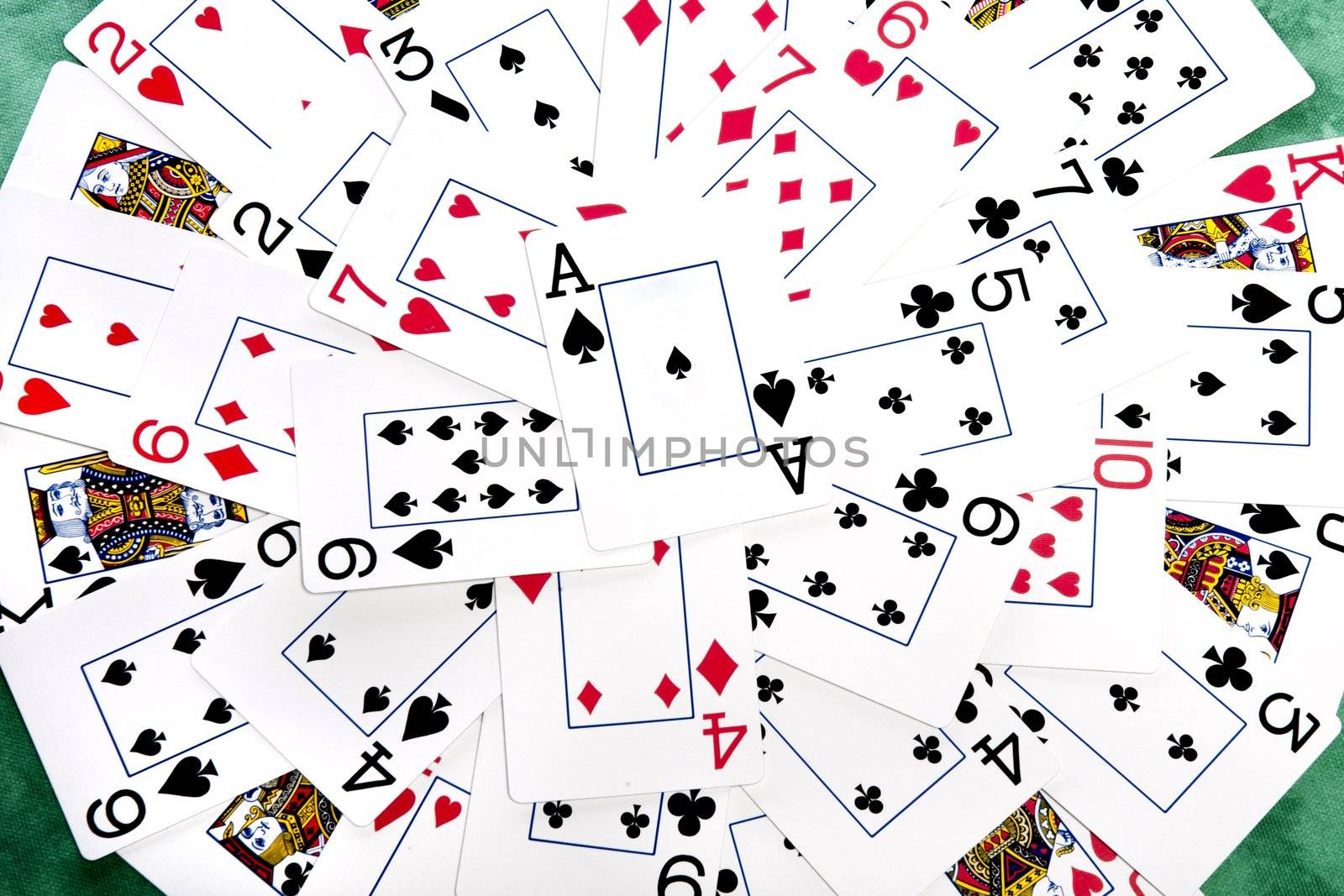 Close up view of a bunch cards spread on a green cloth table forming a circle.