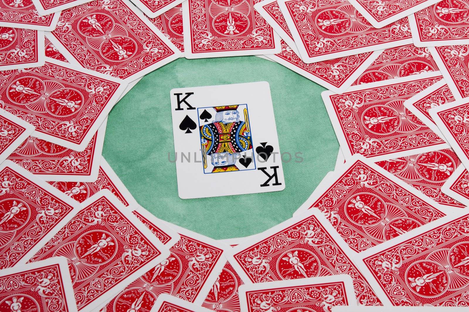 Close up view of a bunch of flipped playing cards spread on a green cloth table.