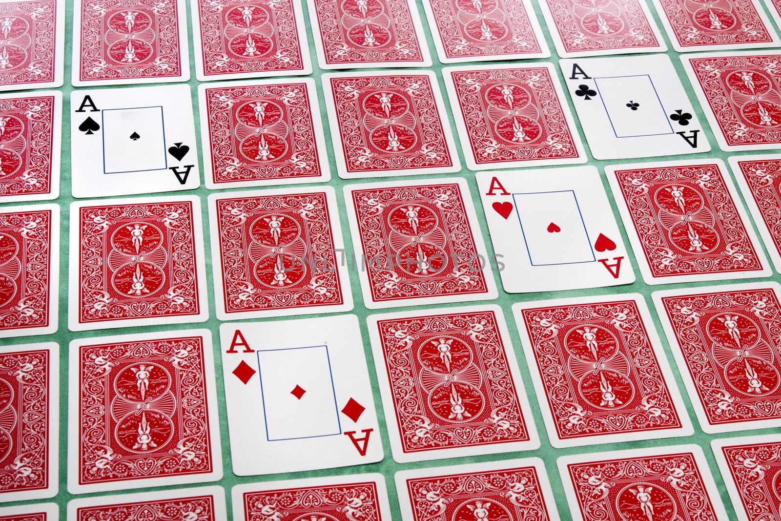 Close up view of a bunch of flipped playing cards spread on a green cloth table.