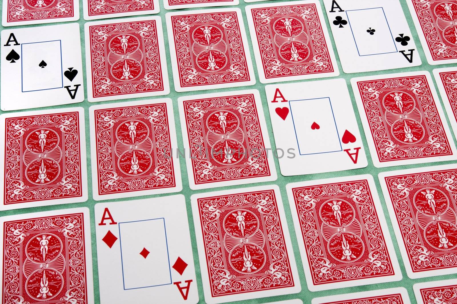 Close up view of a bunch of flipped playing cards spread on a green cloth table.