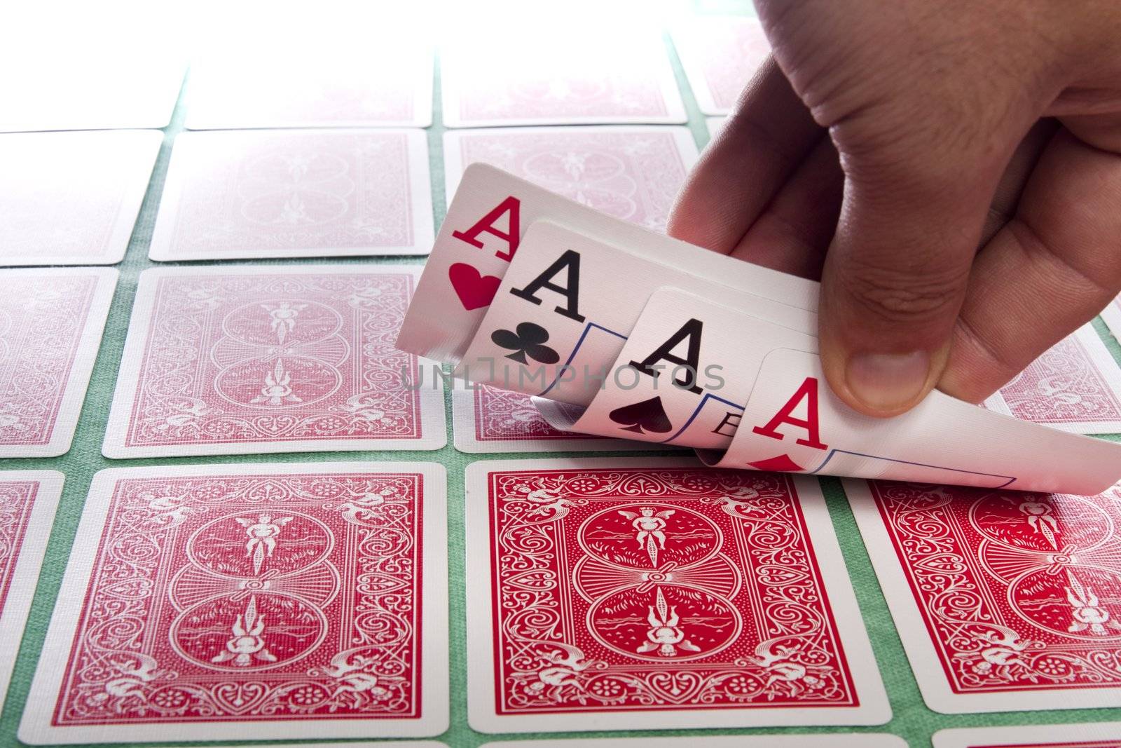 Close up view of a bunch of flipped playing cards spread on a green cloth table.