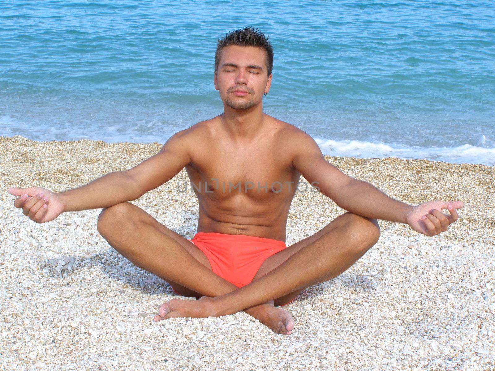 A young man in a meditation on the beach by Larisa13