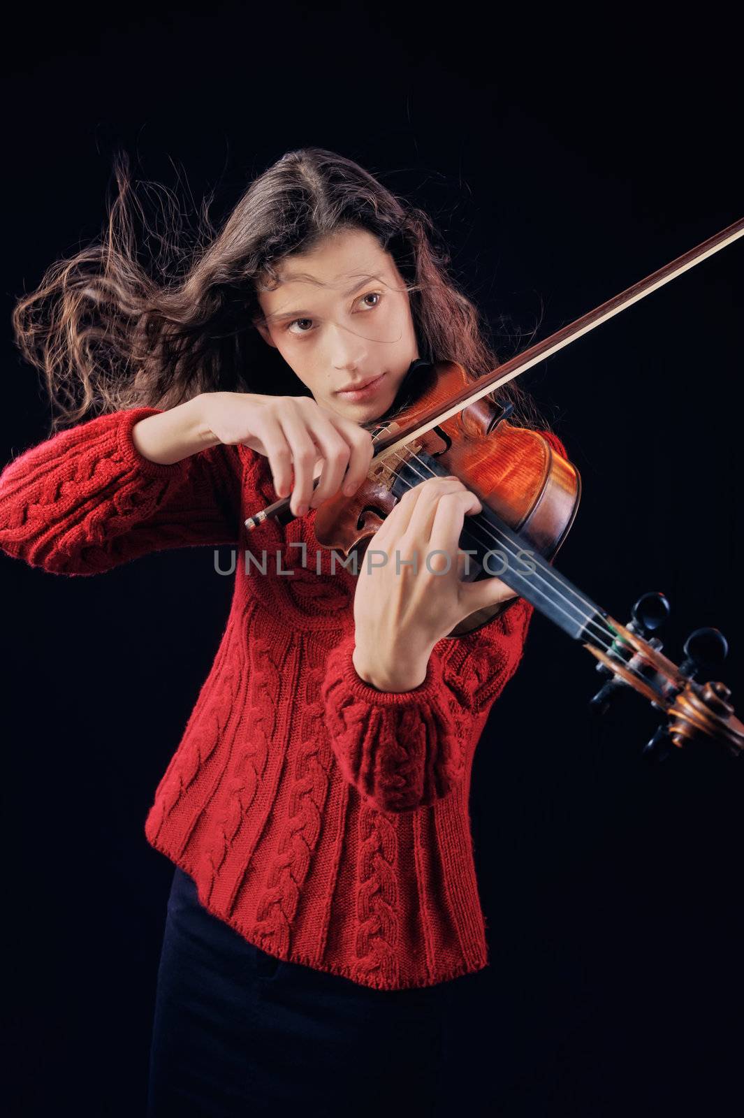 Young woman playing violin. Isolated on the black background