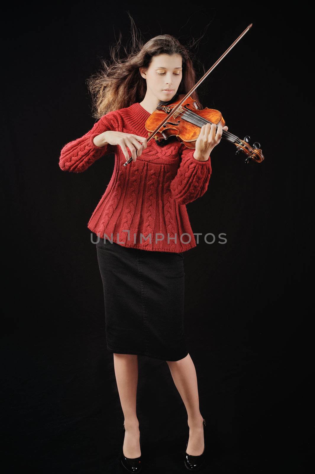 Young woman playing violin. Isolated on the black background