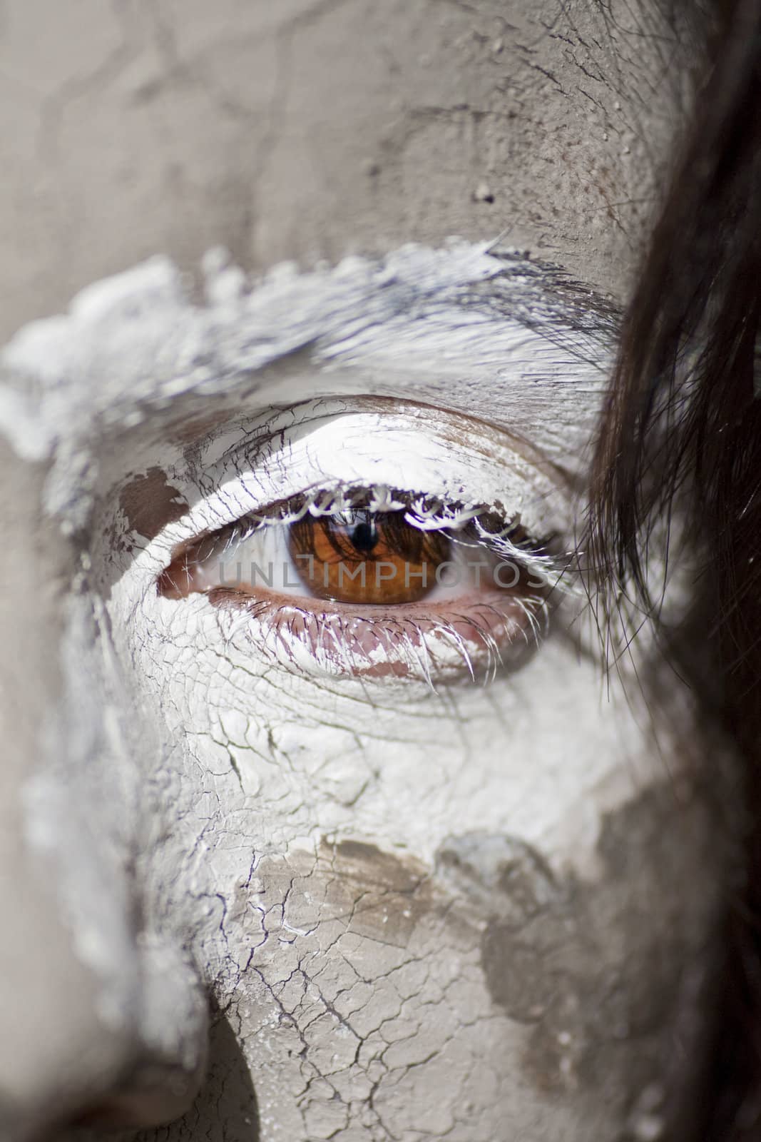 Close up view of a woman's face covered in white and brown clay .