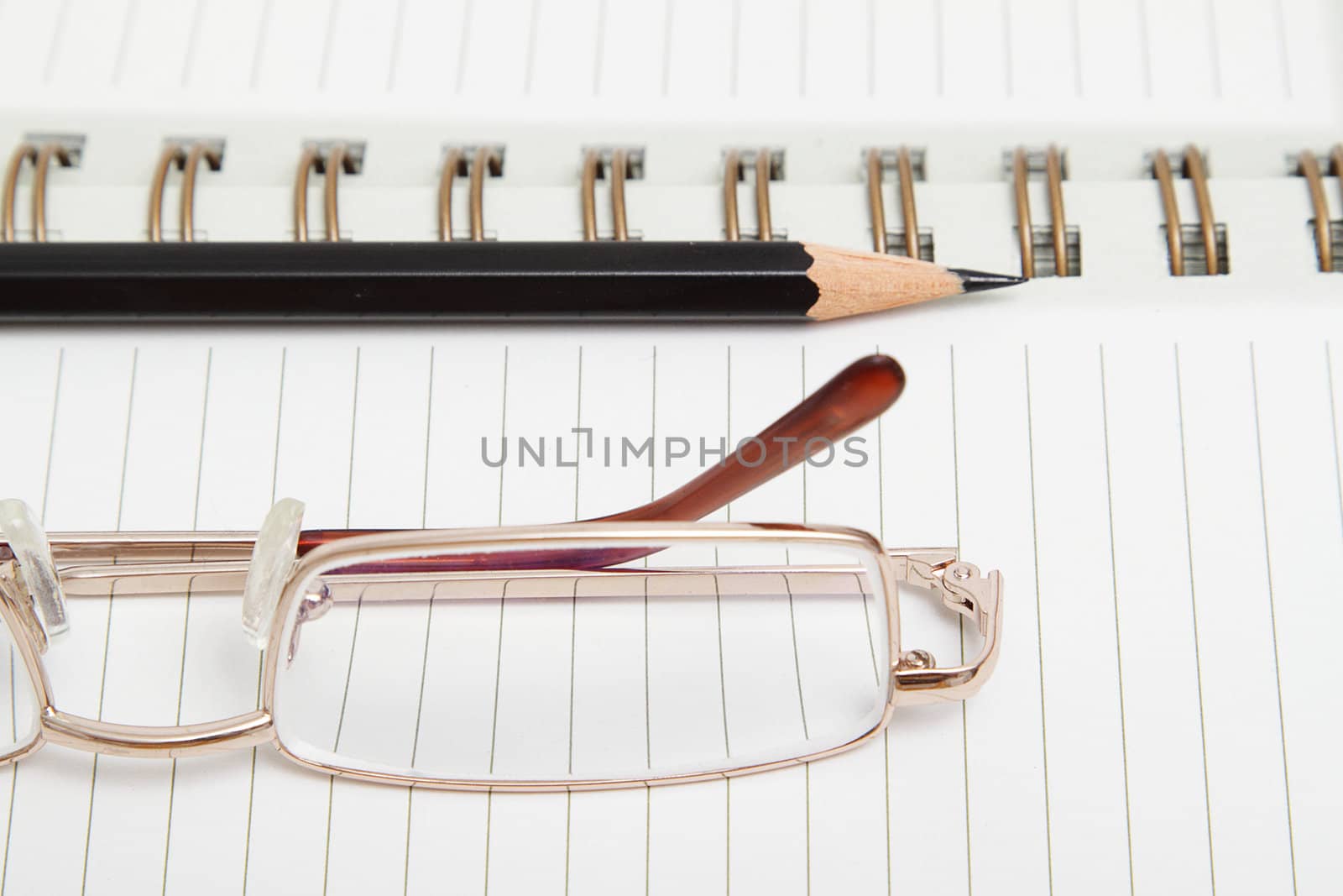 A lined diary with black pencil and reading glasses