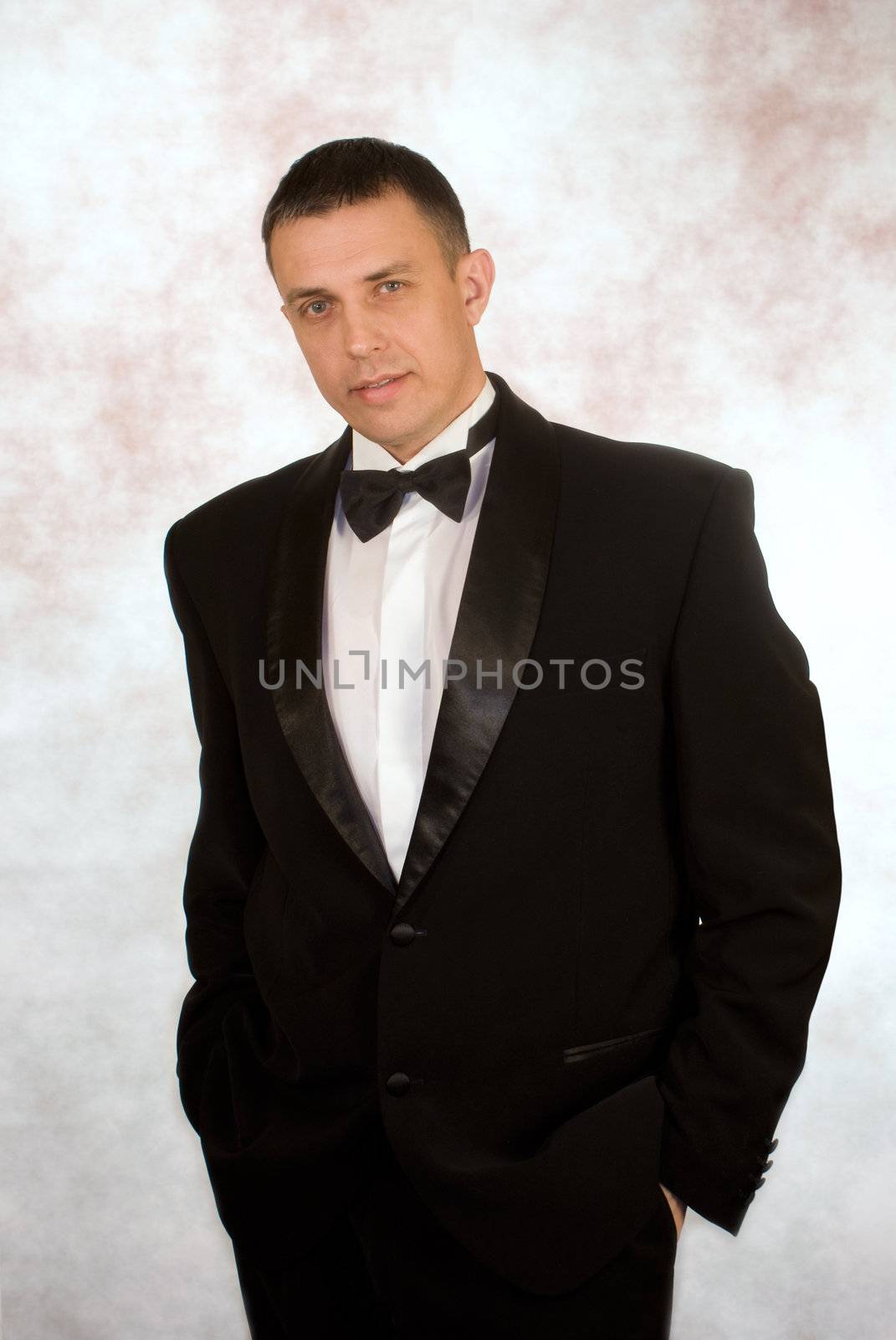 Portrait the man in a classical tuxedo on an abstract background