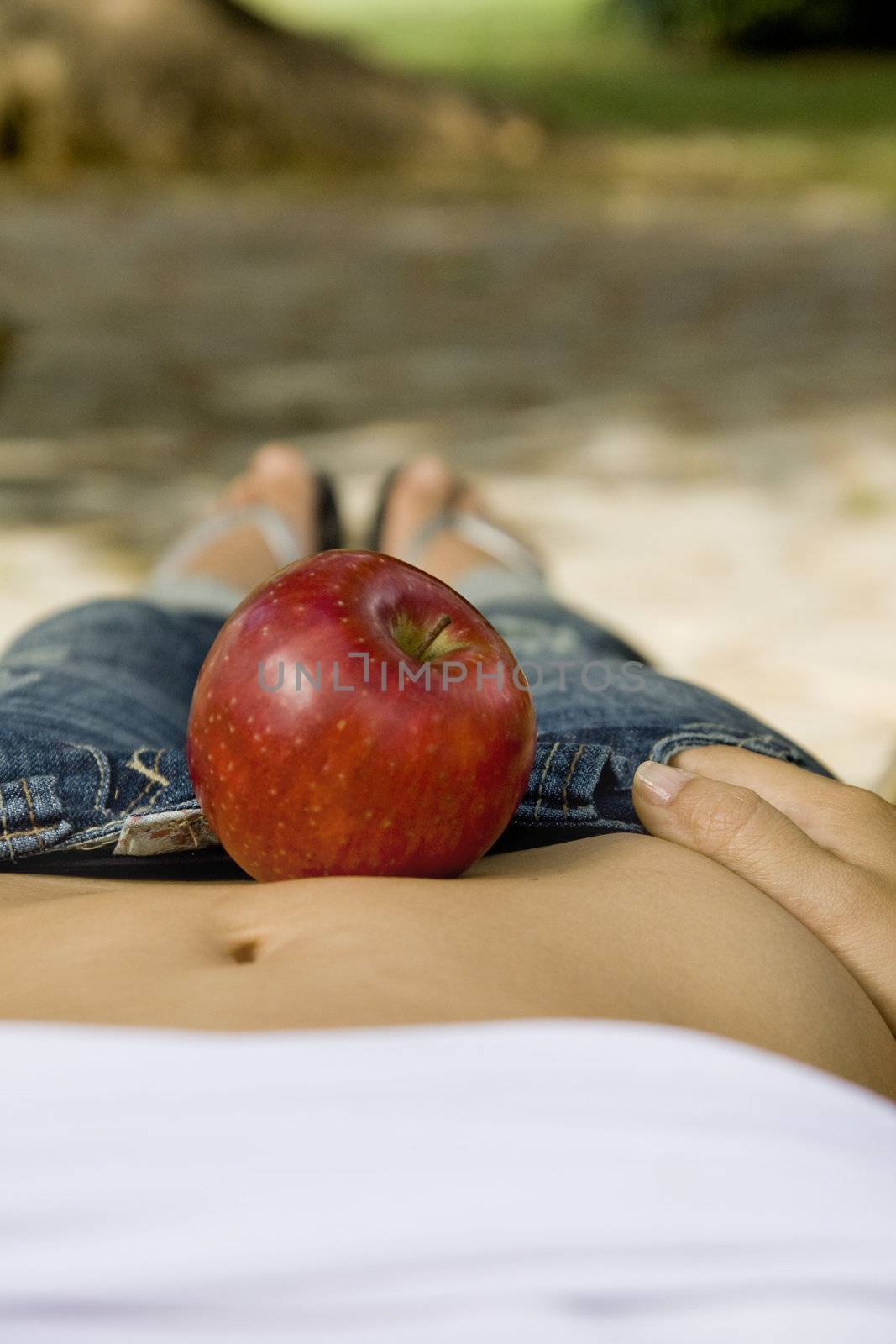 Red apple on the middle of the belly of a slim girl.