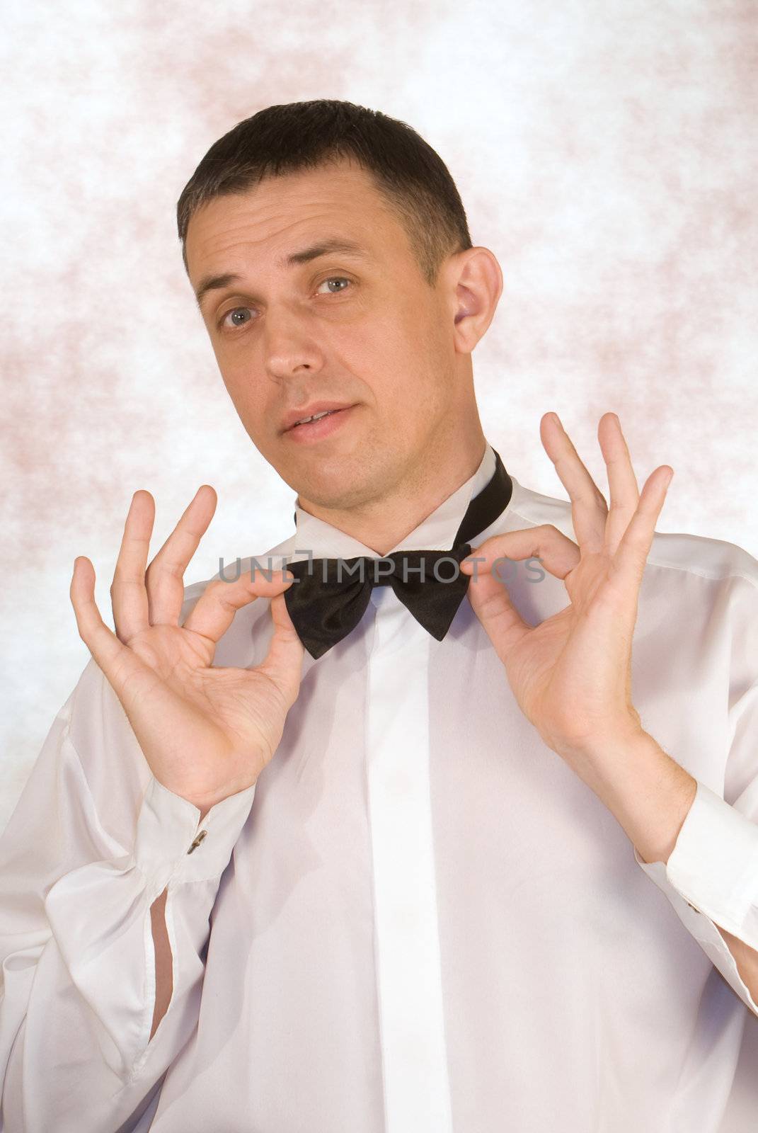 The elegant man gathering for a celebration tries on elegant accessories