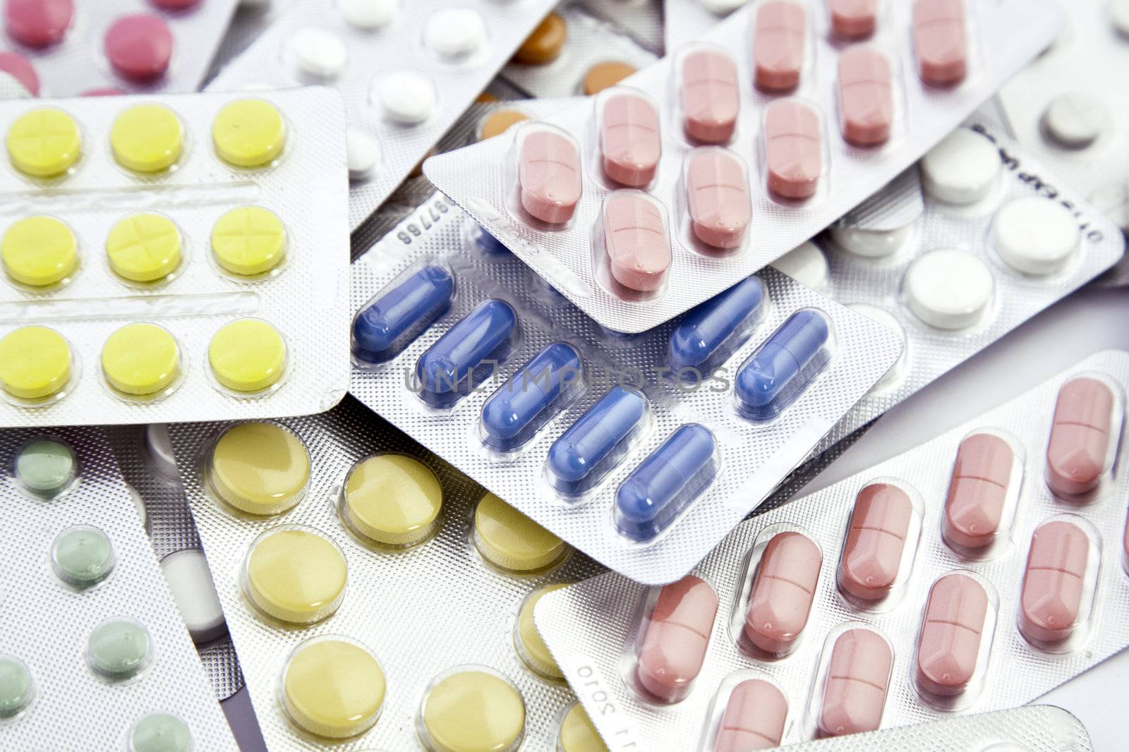white and colored pills in blisters background