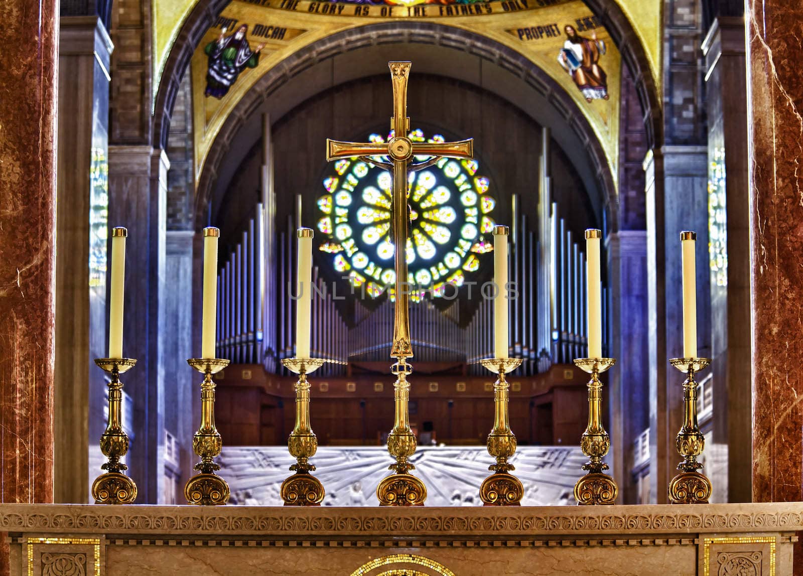 Ornate candlesticks on altar in church with gold cross by steheap