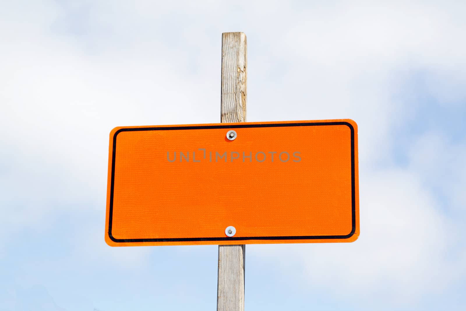 Bright orange road sign over cloudy sky