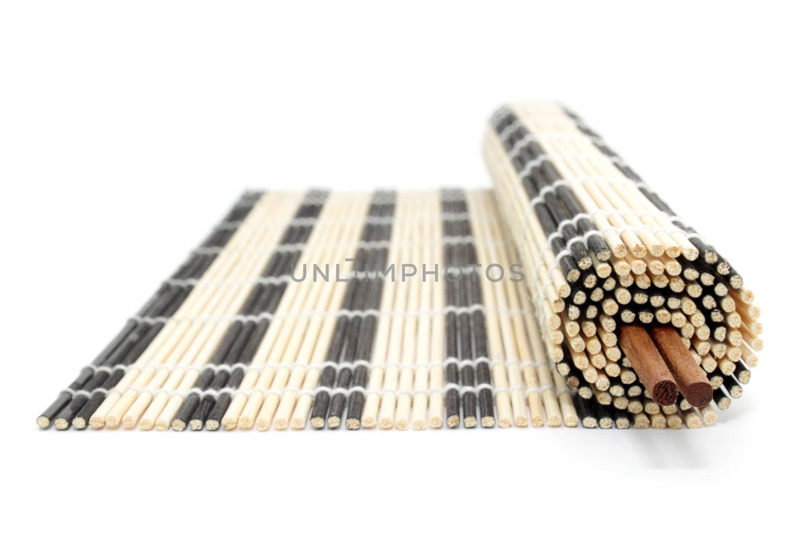 Rolled bamboo mat and chopsticks isolated on white by pulen