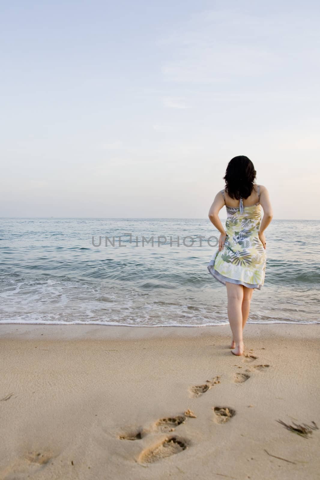 Young woman with dress tries the water on a beach.