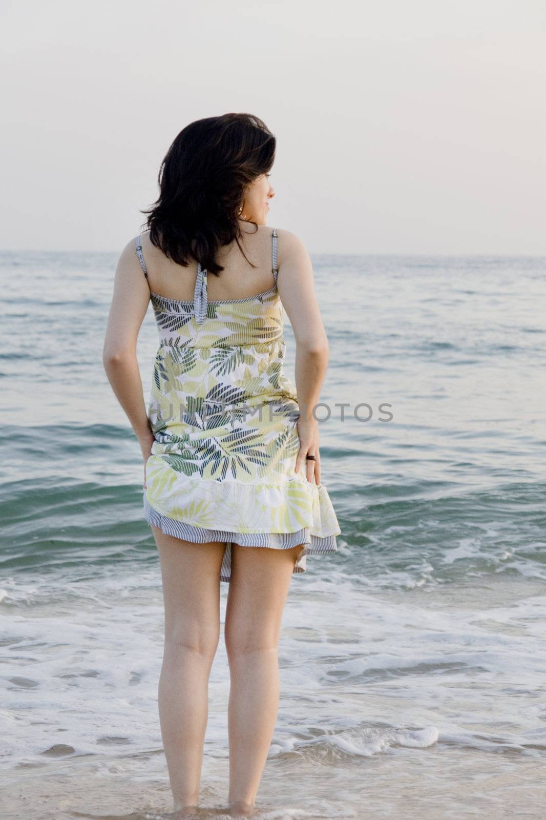 Young woman with dress tries the water on a beach.