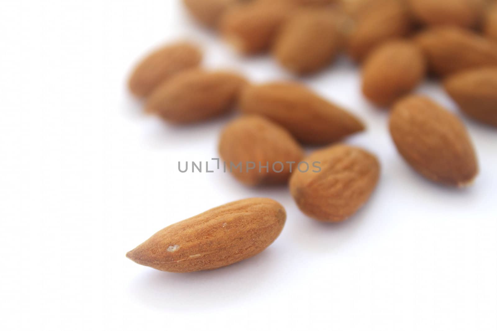 Group of almonds with single one in focus on white background