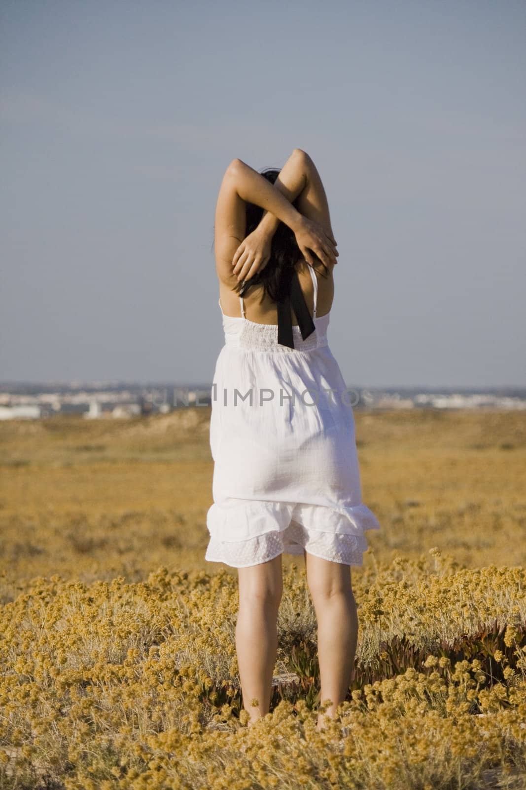 Young woman with dress tries the water on a beach.