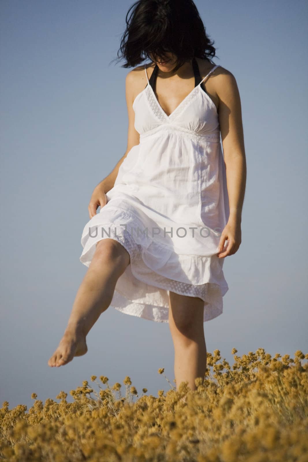 Young woman with white dress surrounded with yellow flowers.