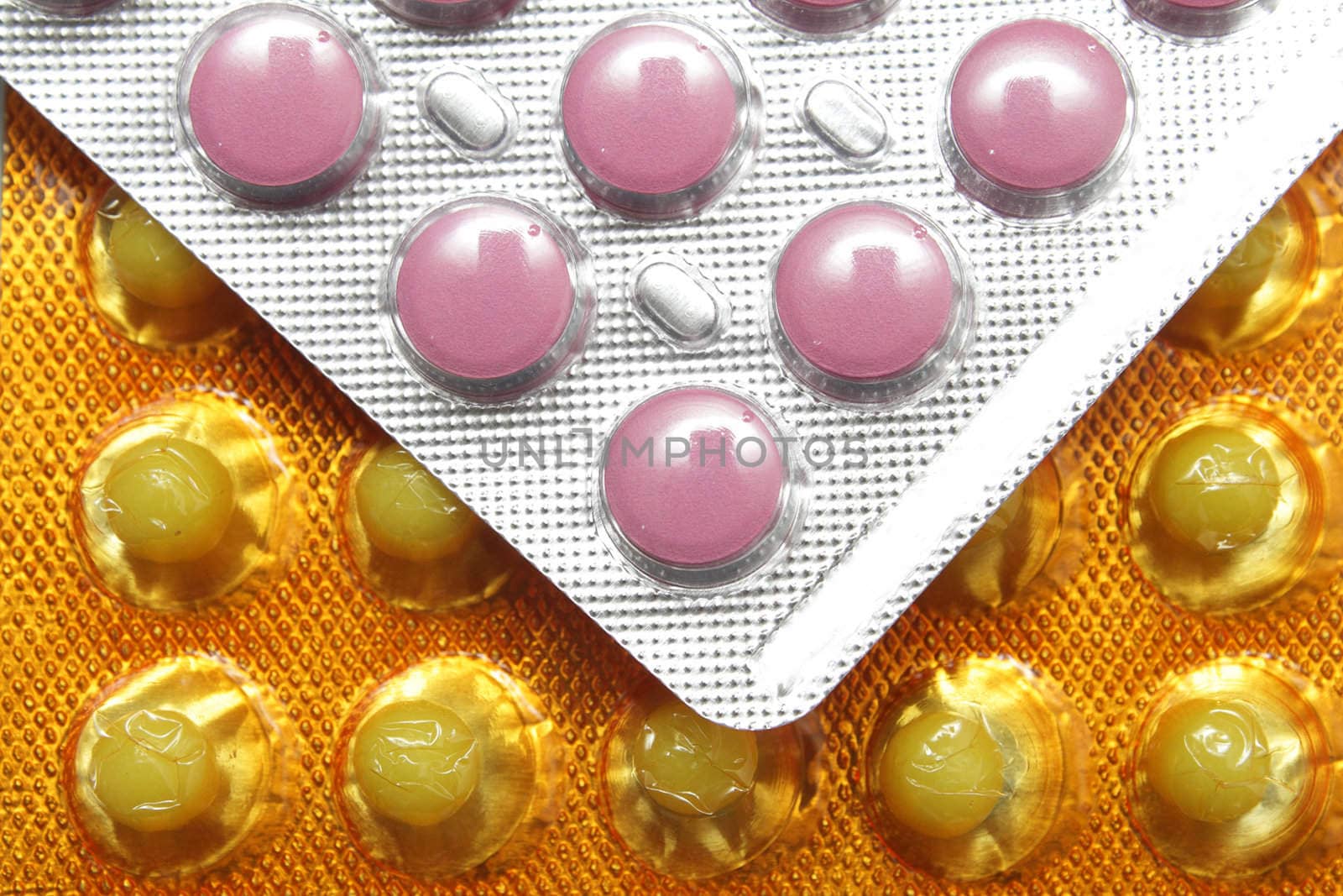 Pink and yellow pills in the silver and yellow packs closeup photo