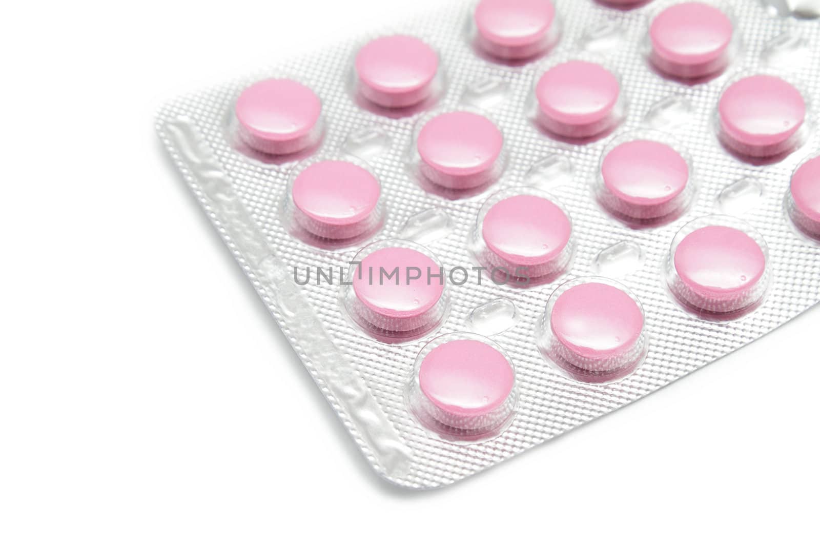 Pink pills in the silver pack on white background