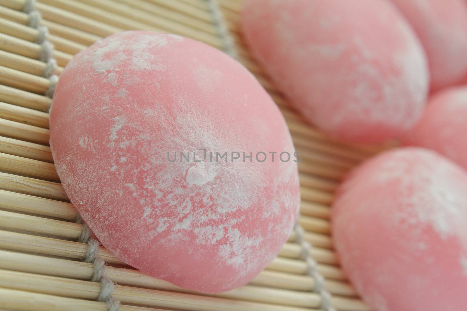 Closeup of pink japanese rice cakes on bamboo mat