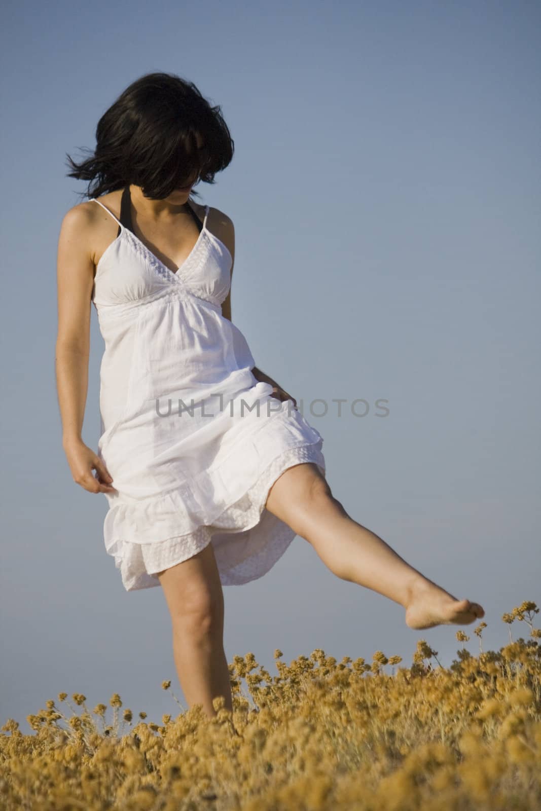 Young woman with white dress surrounded with yellow flowers.