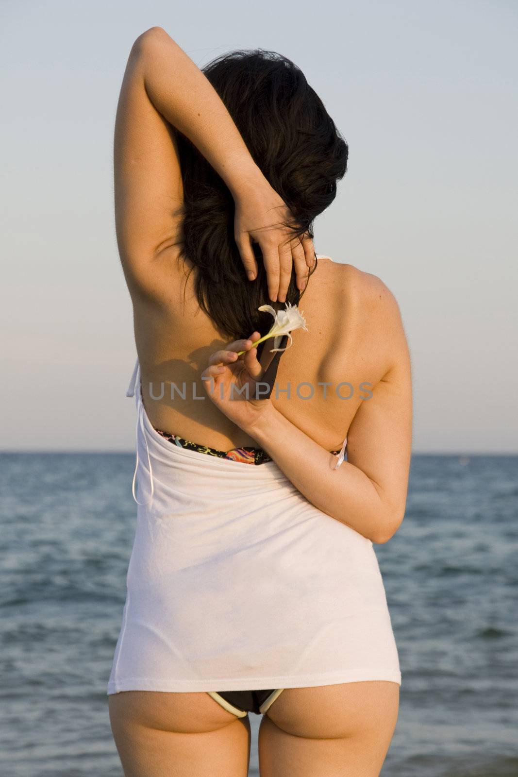 young woman with flower enjoys the sea.
