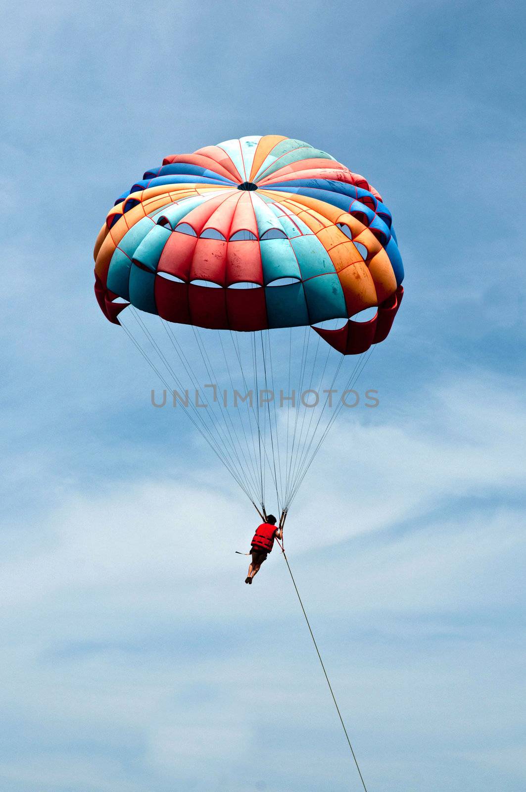 Paraglider launching from the ridge with colorful canopy against a blue sky.